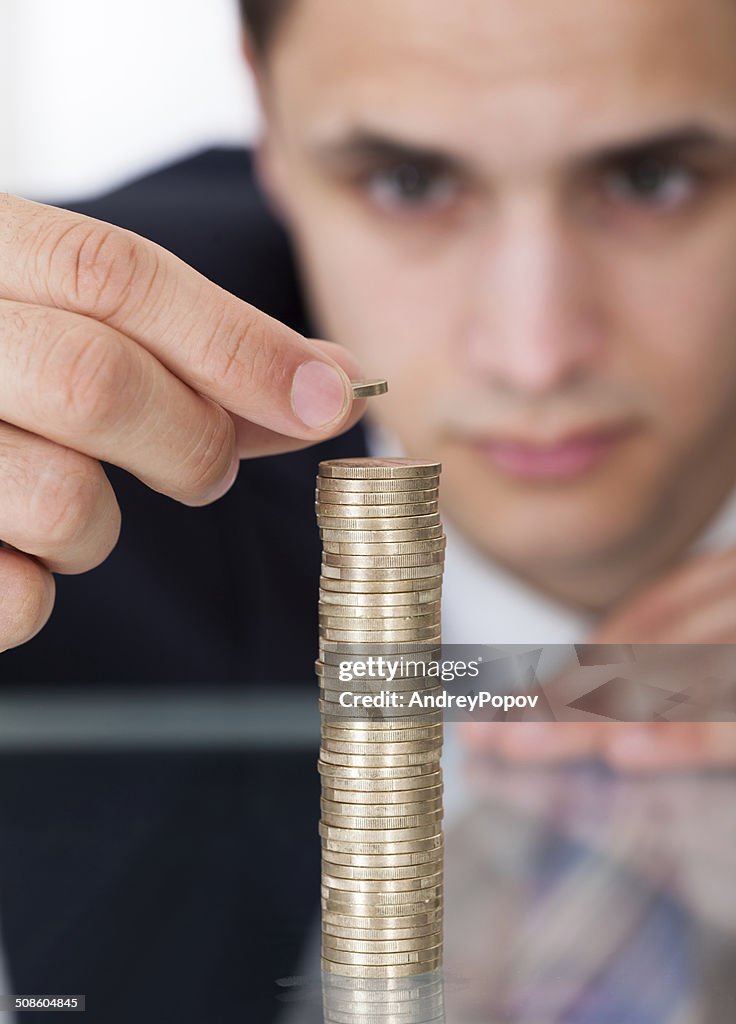 Businessman Stacking Coins At Desk