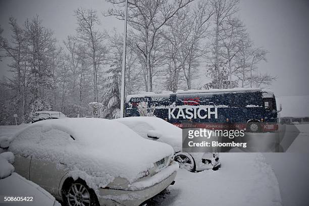 The campaign bus of John Kasich, governor of Ohio and 2016 Republican presidential candidate, sits near snow covered vehicles during a campaign stop...