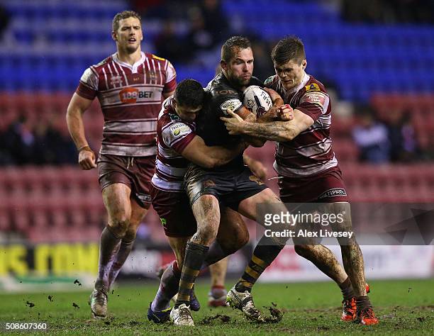 Pat Richards of Catalans Dragons is tackled by Ben Flower and John Bateman of Wigan Warriors during the First Utility Super League match between...