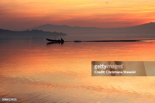 fishing boat gliding across the water - lac trasimeno photos et images de collection