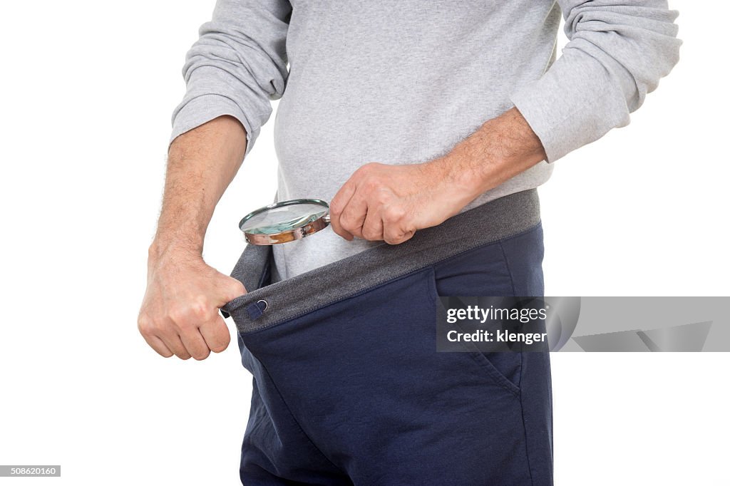 Man with magnifying glass looking into his tracksuit pants