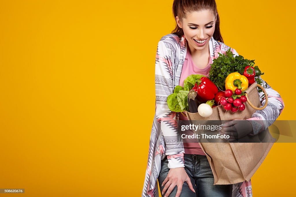 Smiling woman carrying a bag with vegetables