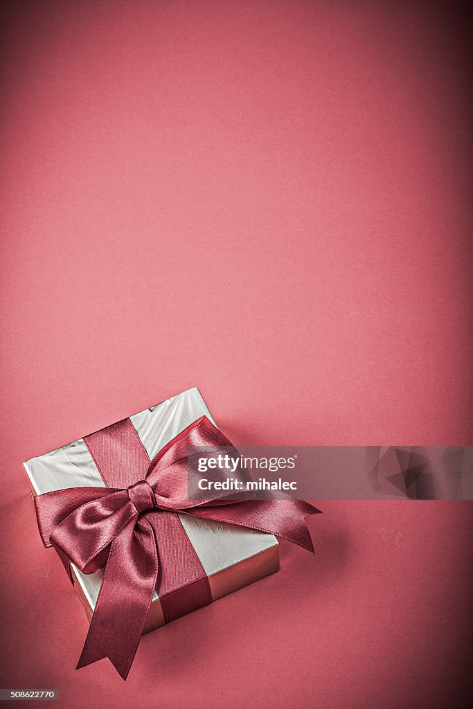 Gift box with tied ribbon on red background holidays concept