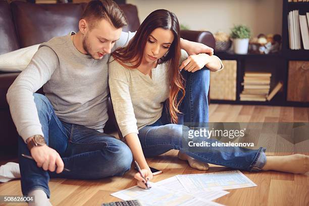 young beautiful couple in home interior - filing documents stock pictures, royalty-free photos & images
