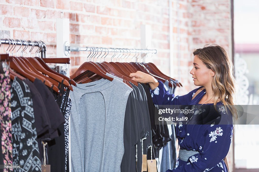 若い女性を見ている衣類の棚に保存