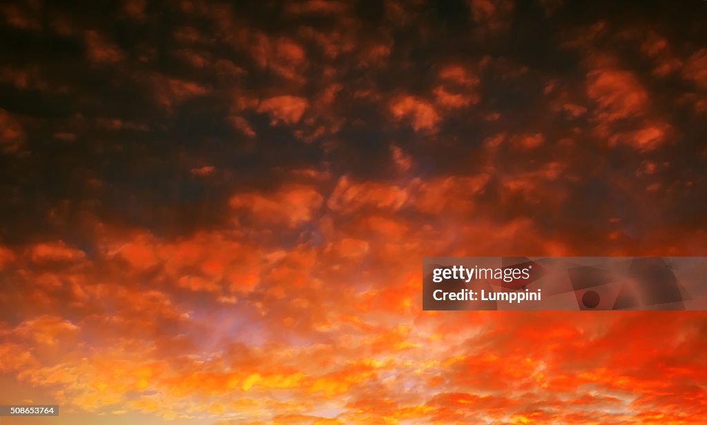 Pocked fiery sky at sunset with sun rays