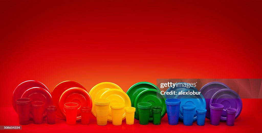 Colored plastic utensils on red background