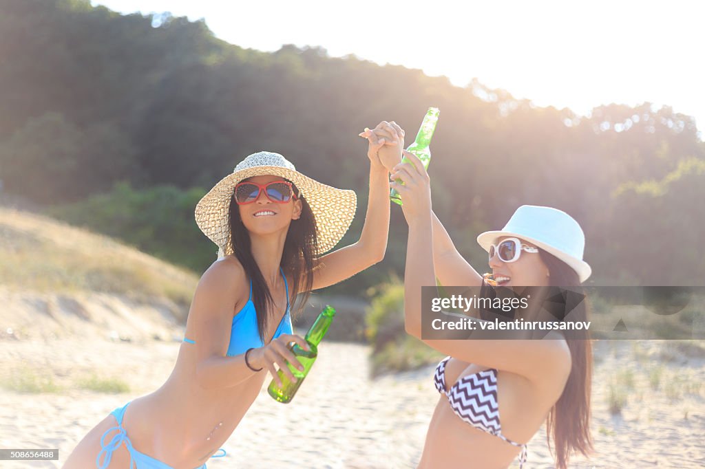 Girls holding beer bottle on the beach
