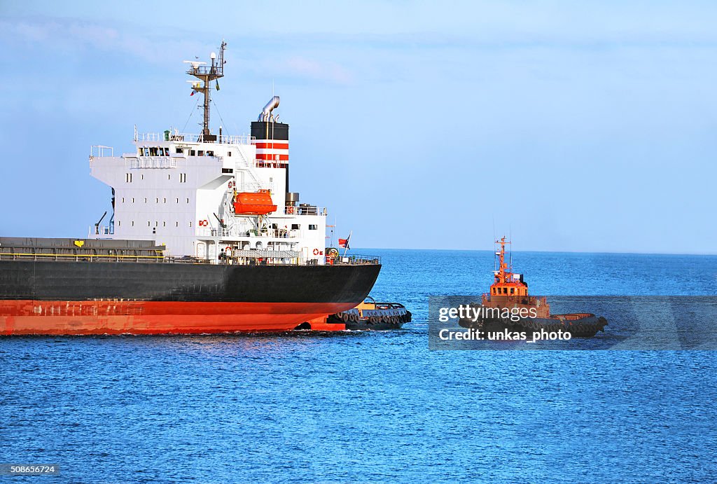 Tugboat assisting cargo ship