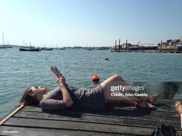 Woman enjoys reading a book by the water in Burnham on Crouch in Essex