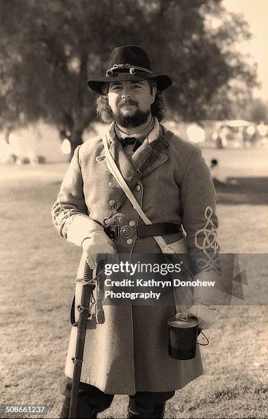 Civil war re-enactment. Very dapperly dressed soldier in uniform. Poses on open field with Sword. Los Angeles, California. Black and white sepia...