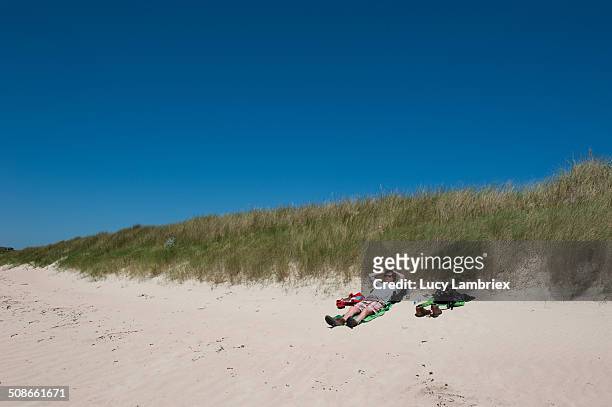 Man lying on beach. Longis Beach Alderney Island.