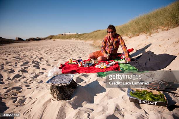 Man on beach with barbecue. Saye beach, Alderney Island. UK.