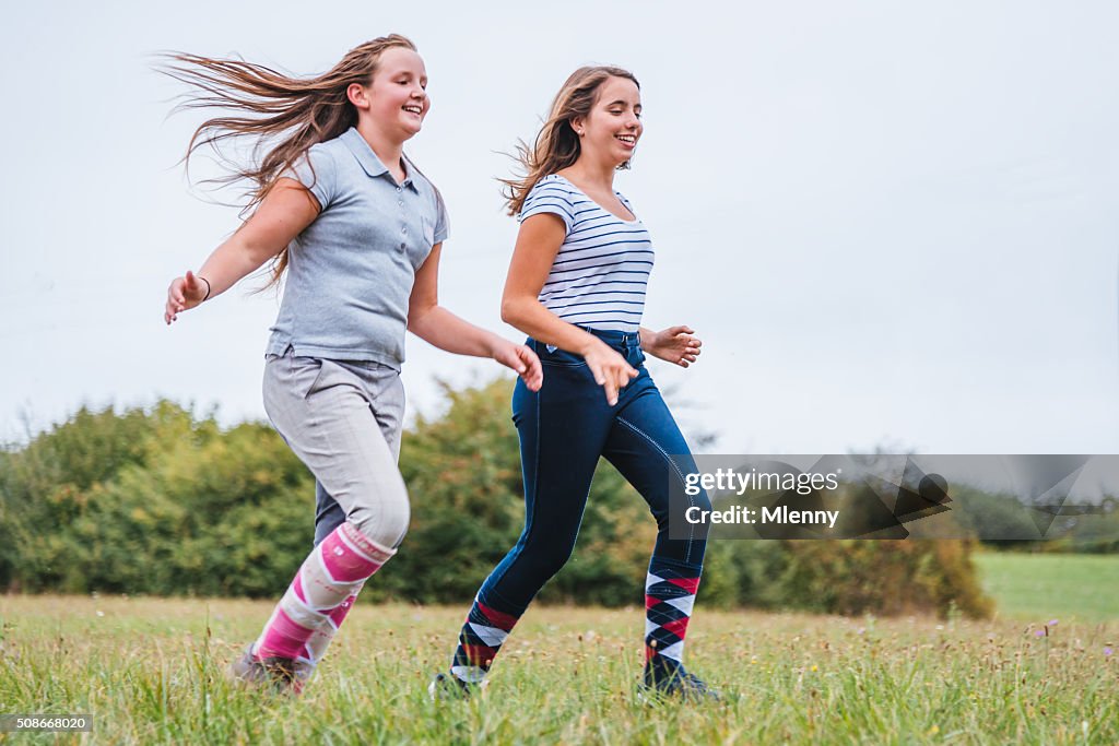Teen girls running together on summer meadow
