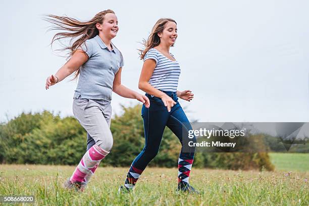 teen girls running together on summer meadow - chubby teenager stockfoto's en -beelden