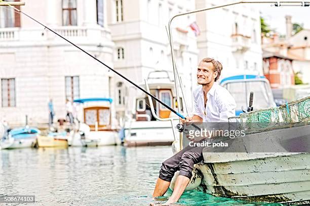 business mann sitzt auf dem rand der boot, angeln - angel brinks stock-fotos und bilder