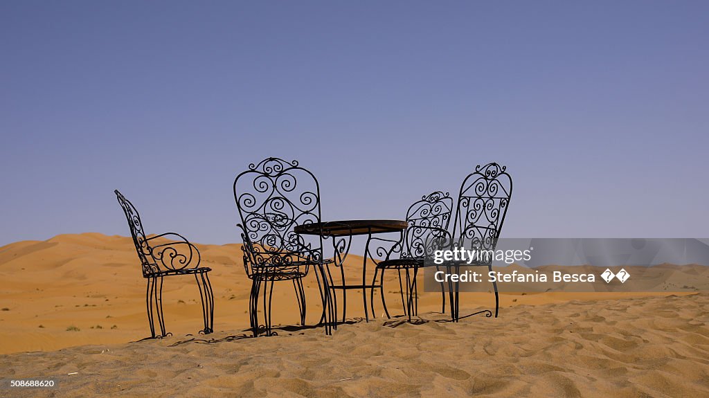 A wrought iron table with chairs among Sahara desert dunes
