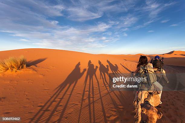 group of tourists going for a caml trip in the middle of deserts with old nomads - arabic people ストックフォトと画像