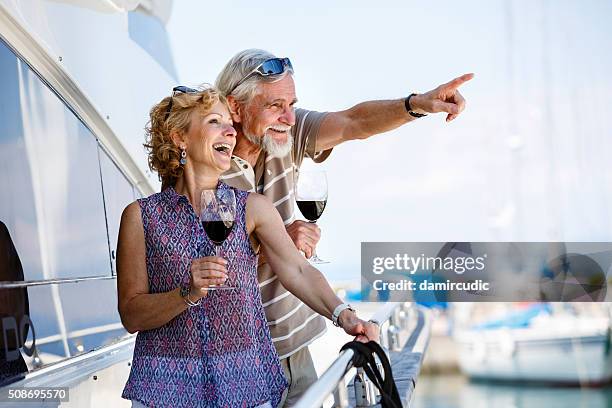 feliz pareja senior disfrutando de vino en yate - cruise vacation fotografías e imágenes de stock