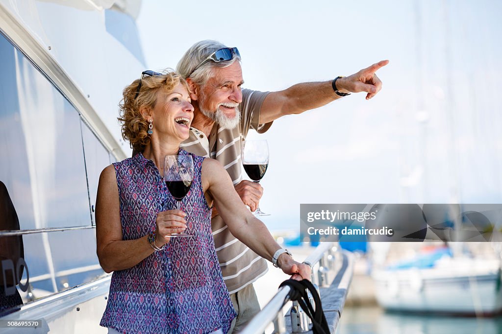 Happy senior couple enjoying wine on yacht