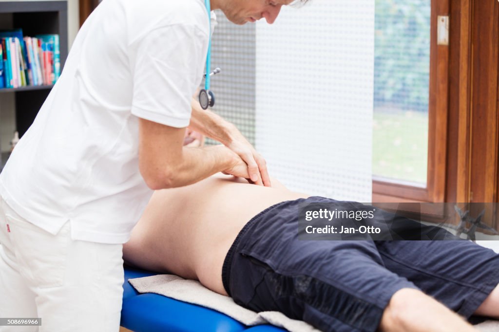 Médico revisando abdomen de edad del paciente