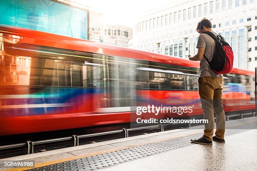 Young man with backpack and headphones waiting for train Young man with backpack and headphones waiting for train