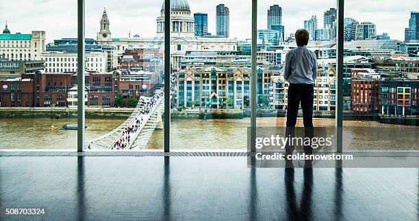 hombre de negocios mira en la ciudad de londres desde su oficina de la ventana - london skyline fotografías e imágenes de stock