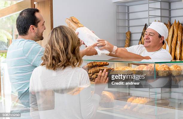 baker serving a couple of customers at the bakery - supermarket bread stock pictures, royalty-free photos & images