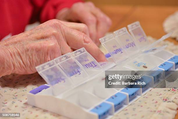 senior woman taking morning pills from weekly pill sorter - weekly pill box stock pictures, royalty-free photos & images