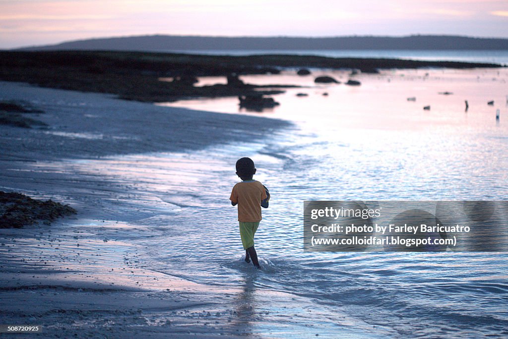 Child running in the beach at sunset