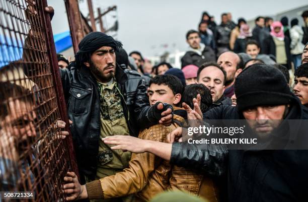 Refugees push each other as they wait for tents as Syrians fleeing the northern embattled city of Aleppo wait on February 6, 2016 in Bab al-Salama,...