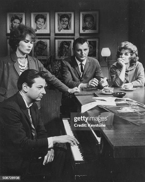 Musician and conductor Andre Previn playing the piano, watched by Dory Langdon, Julie London and Bobby Tramp, circa 1970.