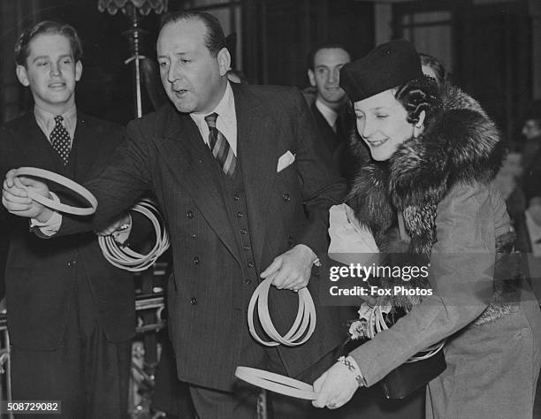 Actor Cecil Parker and Lady O'Neill playing a game of hoop-la as they attend an annual Christmas fair at the May Fair Hotel, London, December 6th...