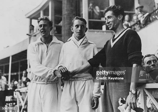 British middle distance runner John Parlett pictured with fellow athletes Roger Bannister and Marcel Hansenne after winning the 800m race at the...