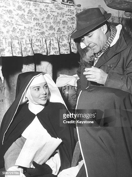 Film director Roberto Rossellini talking to actress Giovanna Ralli, who is wearing a nun's habit, on the set of the film 'Escape by Night', circa...