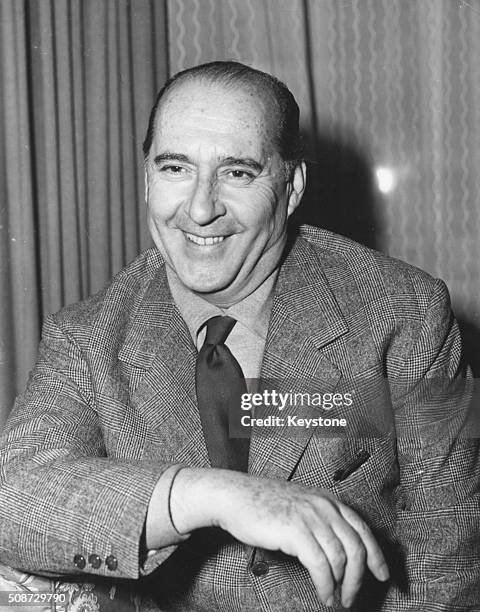 Film director Roberto Rossellini pictured smiling in his hotel room in London, November 26th 1959.