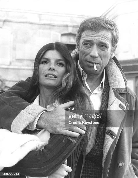 Actor Yves Montand smoking a cigarette with his arm around actress Katharine Ross during a break in filming scenes for 'Le Hasard et la Violence',...