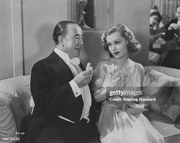 Comedian George Robey and actress Lilli Palmer sitting together in a scene from the film 'A Girl Must Live' 1939.