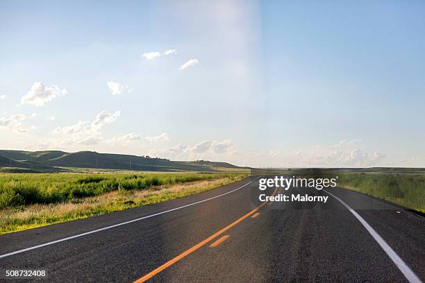 paved road under blue sky in remote landscape - perspectiva de un coche fotografías e imágenes de stock