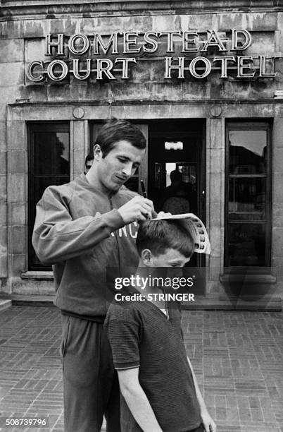 French football player Gerard Hausser signs an autograph on the head of a little boy, on July 12 outside the football World Cup, in England. / AFP /...