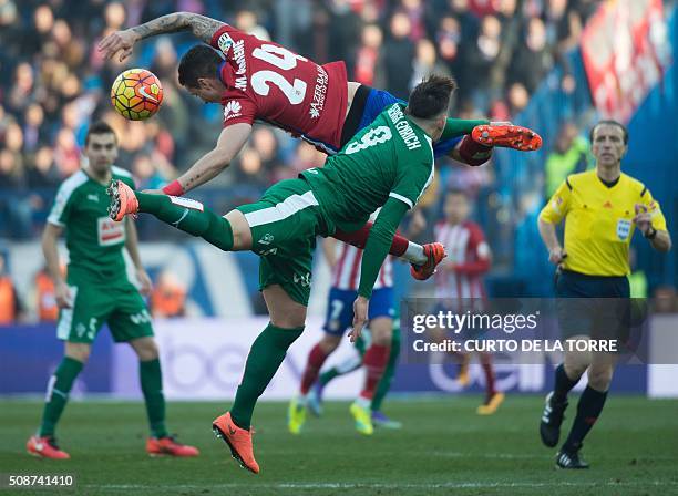 Atletico Madrid's Uruguayan defender Jose Maria Gimenez jumps for the ball with Eibar's forward Sergi Enrich during the Spanish league football match...