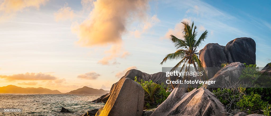 Idyllic tropical island sunset over palm tree beach ocean lagoon