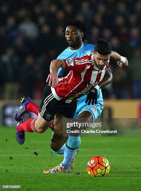 Shane Long of Southampton is challenged by Alexandre Song of West Ham United during the Barclays Premier League match between Southampton and West...