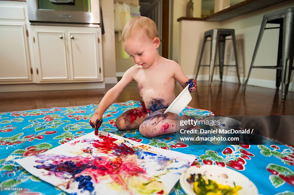 Toddler Girl Happily Finger Painting And Making A Mess High-Res