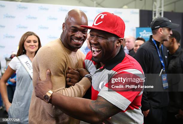Player Adrian Peterson of the Minnesota Vikings and rapper 50 Cent greet one another at the Starkey Hearing Foundation hearing mission during Super...