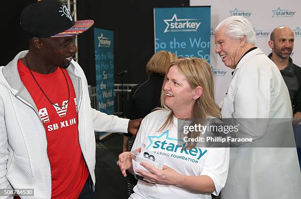 Former NFL player Santonio Holmes checks with a patient as Starkey Hearing Foundation founder William F. Austin looks on at the Starkey Hearing...