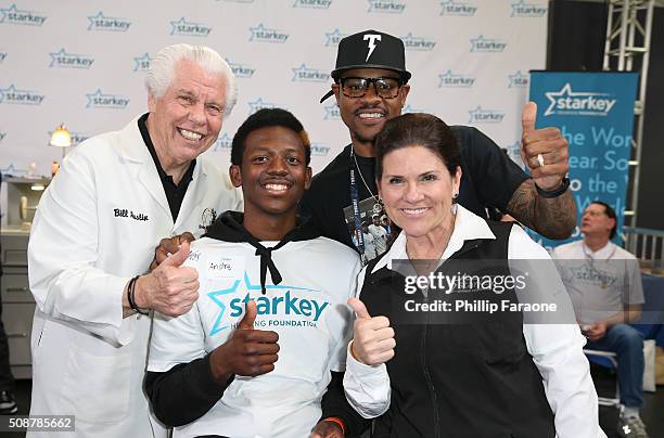 Starkey Hearing Foundation founder William F. Austin, patient Andre, NFL player Ted Ginn Jr.of the Carolina Panthers and Tani Austin give a thumbs up...