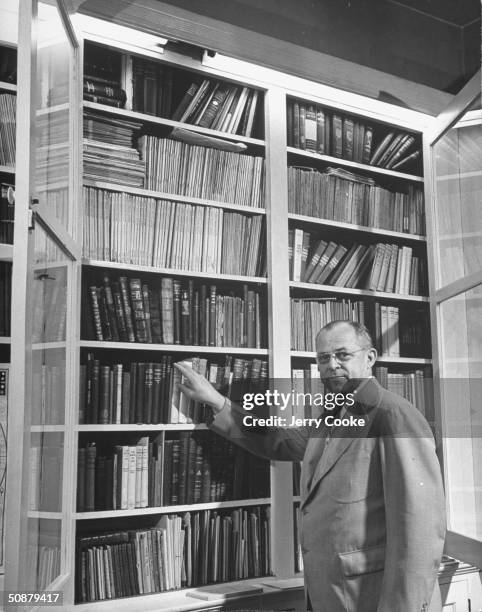 Ernest Grant picking out a book to read in his home library.