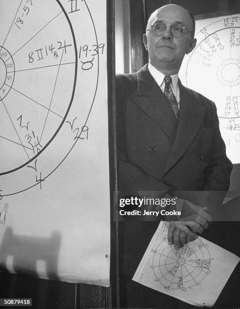 Astrologer Keye Lloyd, standing next to drawings of astrology charts.