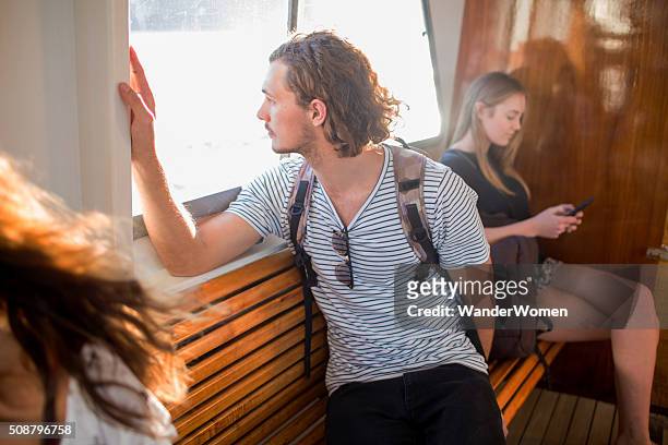 young male communting on passenger ferry looking out window - pittwater stock pictures, royalty-free photos & images